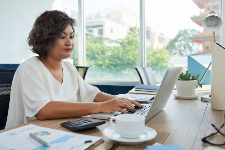 woman with short wavy hair sitting desk office working laptop 1098 17345 768x512